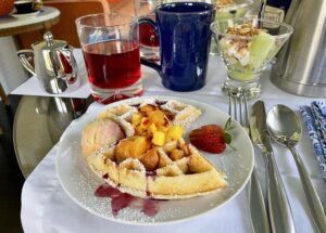 Breakfast setting with waffle and mango, cranberry juice